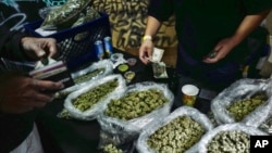 FILE - Seorang penjual memberikan uang kembalian kepada pelanggan ganja di pasar ganja di Los Angeles, 15 April 2019.