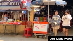 សិស្សសាលាពីរនាក់ ដើរចេញពីអាហារដ្ឋានក្នុងវិទ្យាល័យបាក់ទូក ក្បែរកន្លែងលក់នំចំណី ក្នុងរាជធានីភ្នំពេញ កាលពីថ្ងៃទី២១ ខែកុម្ភៈ ឆ្នាំ២០២៣។