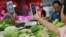 FILE - A customer scans a QR code to pay for vegetables at a morning market in Beijing, Aug. 9, 2023. Indonesia will expand QR systems in part to increase tourism from China, where that payment system is common.