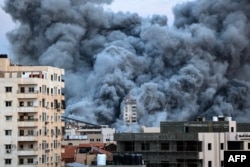 A plume of smoke rises above buildings in Gaza City, Oct. 7, 2023 during an Israeli airstrike that hit the Palestine Tower building.
