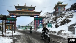 Pengendara sepeda motor menyeberang ke jalur Sela Himalaya yang sarat salju di Tawang di negara bagian Arunachal Pradesh, timur laut India, 5 April 2023.