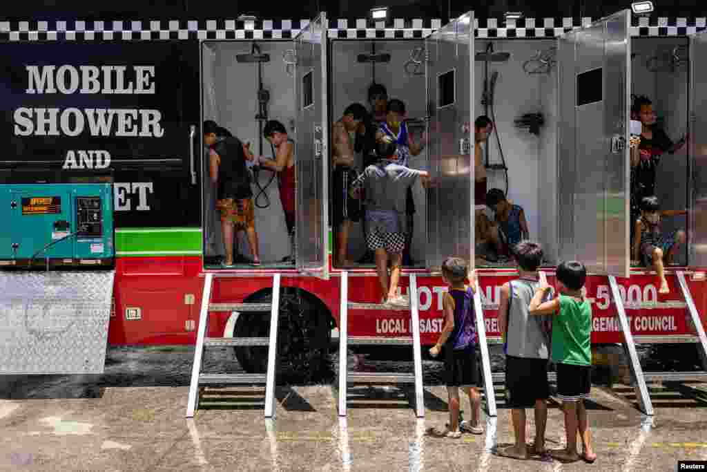Anak-anak menyiram tubuhnya di ruang basuh di atas truk (mobile shower) yang disediakan pemerintah setempat di tengah panas ekstrem di Valenzuela, Metro Manila, Filipina, 2 Mei 2024.