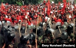 Polisi mencegah para pendukung Megawati Soekarnoputri yang menghadapi oposisi dari Ketua PDI Soerjadi yang dibekingi pemerintah dalam demo pada 20 Juni 1996. Satu bulan kemudian, konflik internal partai berujung pada Kerusuhan 27 Juli atau Kudatuli. (Foto: Enny Nuraheni/Reuters)