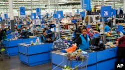FILE - Cashiers process purchases at a Walmart Supercenter in North Bergen, N.J., on Feb. 9, 2023.