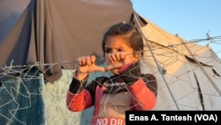 A child peers over fencing at a makeshift camp in Rafah, Gaza, on March 2, 2024. Doctors say children in Gaza’s north are starving to death and children in the south all have visible symptoms of physical and psychological damage from war and hunger.