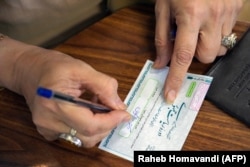 Seorang perempuan Iran sedang menyiapkan surat suara di sebuah tempat pemungutan suara (TPS) di Teheran dalam pemilihan presiden, Jumat, 28 Juni 2024. (Foto: Raheb Homavandi/AFP)