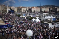 People gather to watch the welcoming ceremony of Belem, the three-masted sailing ship which is carrying the Olympic flame, in Marseille, southern France, May 8, 2024.
