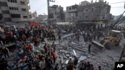 Palestinians search for bodies and survivors in the rubble of a residential building destroyed in an Israeli airstrike, in Rafah, southern Gaza Strip, Dec. 20, 2023. 