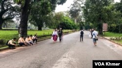 មគ្គទេសក៍ទេសចរ​មួយ​ចំនួន​អង្គុយ​រងចាំ​ភ្ញៀវនៅ​មុខ​បរិវេណ​នៃ​ប្រាសាទ​អង្គរវត្ត នៅ​ខេត្ត​សៀមរាប​ កាលពី​ថ្ងៃទី ៣ ខែតុលា ឆ្នាំ ២០២៣។ (ធីតា វីន/វីអូអេ) 