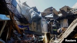 Seorang petugas pemadam kebakaran bekerja di dalam gedung Universitas Ekonomi dan Perdagangan yang habis terbakar di Donetsk, Ukraina yang dikuasai Rusia, 6 Agustus 2023. (Foto: Reuters)