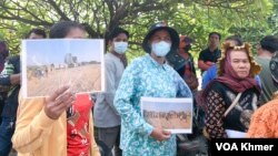 ប្រជាពលរដ្ឋរស់នៅក្នុងស្រុកកណ្តាលស្ទឹង ខេត្តកណ្តាល លើករូបថតដែលពួកគេថាក្រុមហ៊ុន OCIC ចាក់ដីលុបប្រឡាយទំនប់៩៤ នៅក្នុងទីធ្លាសាលាខេត្តកណ្តាល កាលពីថ្ងៃទី២៧ ខែមីនា ឆ្នាំ២០២៤។ (លាស់ លីបលីប/វីអូអេ)