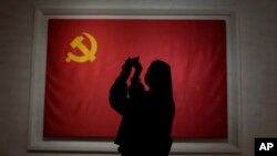 រូបឯកសារ៖ ពលរដ្ឋម្នាក់ថតរូបទង់បក្សកុម្មុយនិស្តចិន នៅសារមន្ទីរមួយក្នុងទីក្រុងប៉េកាំង ប្រទេសចិន កាលពីថ្ងៃទី ១២ ខែវិច្ឆិកា ឆ្នាំ ២០២១។ 