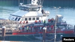 Orang-orang, yang diyakini sebagai migran, turun dari kapal Pasukan Perbatasan di pusat pemrosesan Pasukan Perbatasan, Dover, Inggris, 10 Desember 2022. (REUTERS/Peter Nicholls)