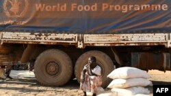 FILE - Seorang perempuan pengungsi duduk di samping truk Program Pangan Dunia (WFP) saat pembagian makanan di Bentiu pada 6 Februari 2023. (Simon MAINA/AFP)