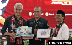 Calon presiden Ganjar Pranowo (kiri) dan calon wakil presiden Mahfud MD (kanan) menyerahkan visi dan misi mereka kepada Ketua KPU Hasyim Asyari (tengah) pada Kamis (19/10) di Jakarta. (VOA/Indra Yoga)