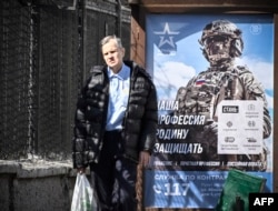 ARHIVA - Muškarac hoda pored oglasa koji promoviše potpisivanje ugovora sa vojskom, na kojem piše "Naš posao - da branimo otadžbinu"