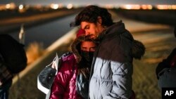 FILE - A couple from Cuba wait to be processed to seek asylum after crossing the border into the United States, near Yuma, Arizona, Jan. 6, 2023.