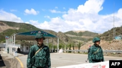 FILE - Men guard an Azerbaijani checkpoint set up at the entry of the Lachin corridor, the Armenian-populated breakaway Nagorno-Karabakh region's only land link with Armenia, by a bridge across the Hakari River, on May 2, 2023. 