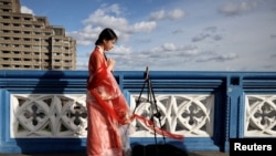 FILE - A Chinese student who calls herself Evie makes a video for her followers on Douyin, a Chinese social media network, on Tower Bridge in London, March 25 2023. In late May 2024, Douyin announced a new verification mechanism for suspected fake content.