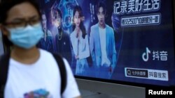 FILE - A pedestrian wearing a face mask following the coronavirus disease (COVID-19) outbreak walks past an advertisement of TikTok (Douyin) at a bus stop in Beijing, China Aug. 24, 2020.