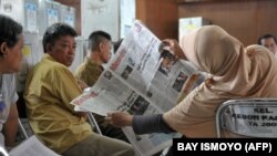 Petugas pemungutan suara dan saksi membaca berita saat penghitungan suara dalam pemilu legislatif di Jakarta, 12 April 2014. (Foto: Bay Ismyoyo/AFP)