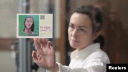 FILE - Russian-American journalist for Radio Free Europe/Radio Liberty Alsu Kurmasheva, holds a card reading "She's expected home" as she attends a court hearing in Kazan, Russia, April 1, 2024. 