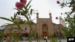 FILE - This picture taken n July 19, 2023, shows people passing an old disused mosque in Artux, northwestern China's Xinjiang region.