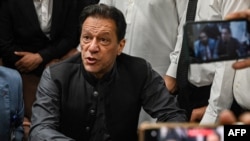 Mantan perdana menteri Pakistan, Imran Khan memberi isyarat setelah tiba di kantor pendaftaran di Pengadilan Tinggi Lahore untuk menandatangani surat jaminan untuk jaminan dalam berbagai kasus, di Lahore pada 3 Juli 2023. (Foto: AFP)