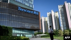 Seorang pria berjalan melewati markas raksasa teknologi asal China, Tencent, di Shenzen, provinsi Guangdong, pada 10 Juli 2022. (Foto: AFP/Jade Gao)