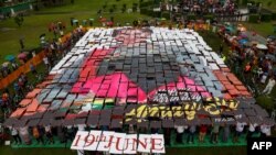 FILE - Para pendukung membuat potret mosaik Aung San Suu Kyi dari plakat, dalam acara perayaan ulang tahunnya yang ke-74 di taman Mahabandula di Yangon, 19 Juni 2019.