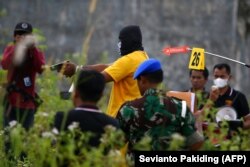Tersangka memeragakan saat mengacungkan pistol ke arah korban dalam rekonstruksi pembunuhan empat orang asli Papua oleh sejumlah anggota TNI di Mimika, Papua, 3 September 2022. (Foto: Sevianto Pakiding/AFP)
