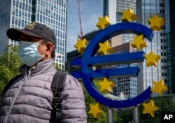Seorang pria berjalan melewati patung Euro di depan Bank Sentral Eropa lama di Frankfurt, Jerman, Selasa, 5 Mei 2020. (AP/Michael Probst)