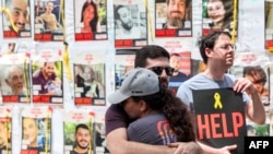 在2023年10月7日遭哈马斯武装分子劫持的人质照片前，至今被扣押的人质家属与支持者在特拉维夫以色列国防部外举行抗议活动，呼吁政府采取行动释放人质。(2024年4月25日)