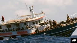 Orang-orang di atas kapal nelayan melambaikan tangan saat didekati oleh awak kapal penyelamat Geo Barents Selasa, 4 April 2023, di perairan internasional lepas pantai Libya. (AP/Salvatore Cavalli)