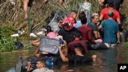 FILE - Migran Venezuela Luis Parra (ketiga dari kanan), bergabung dengan migran lainnya menyeberangi sungai Rio Grande, terlihat dari Matamoros, Meksiko, 10 Mei 2023. (AP/Fernando Llano)