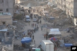 Warga Palestina berjalan melewati puing-puing setelah serangan udara dan darat Israel di kota Khan Younis, Jalur Gaza selatan, Rabu 15 Mei 2024.