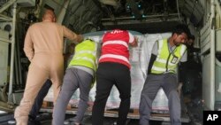 在沙特一个机场一队利雅得救援人员将运往苏丹的救援物质推进一架军用运输机的机舱内。（2023年5月10日）