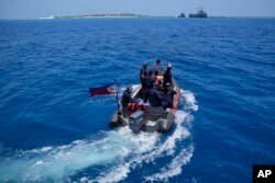 Philippine coast guard personnel from BRP Malabrigo go towards Philippine-claimed island of Thitu, locally known as Pag-asa island, at the South China Sea, April 21, 2023.