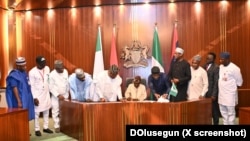 Shugaba Bola Tinubu a zagaye da wasu jami'in gwamnatinsa yayin da ya rattaba hanu akan dokar rancen dalibai.