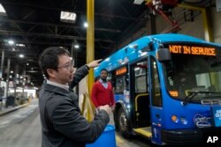 Asisten kepala teknisi peralatan bus Chicago Transit Authority Richard Lin berbicara tentang fitur bus listrik saat mengisi daya di garasi West Side, Chicago, Selasa, 14 Februari 2023. (AP/Erin Hooley)