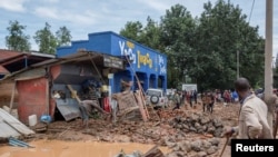 Para warga berusaha menyelematkan barang-barang mereka yang tersapu banjir setelah hujan lebat mengakibatkan banjir dan tanah longsor di distrik Rubavu, Rwanda, pada 3 Mei 2023. (Foto: Reuters/Jean Bizimana)