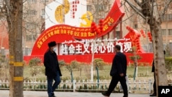 资料照：新疆和田居民走过街头竖立的社会主义核心价值观的宣传牌。（2021年3月22日）