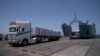 FILE - Trucks arrive loaded with humanitarian aid at the U.S.-built floating pier before reaching the beach on the Gaza coast, June 25, 2024. U.S. defense officials said on July 12, 2024, that there is no date set for re-attaching the pier, which is currently dismantled.