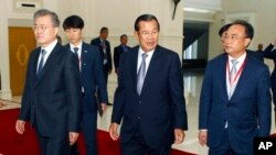 FILE - Cambodia's Prime Minister Hun Sen, center, walks together with South Korea President Moon Jae-in, left, as Cambodian tycoon Kith Meng, right, accompanies them before a business forum at the Peace Palace, in Phnom Penh, Cambodia, March 15, 2019. 