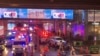 Ambulances wait outside an exit of the Siam Paragon Mall while shoppers rush out after shots are fired inside, in Bangkok, Thailand, Oct. 3, 2023.