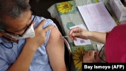 Seorang pria sedang diimunisasi vaksin COVID-19 di sebuah puskesmas di Jakarta, 1 Februari 2023. (Foto: Bay Ismoyo/AFP)