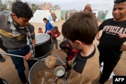 Anak-anak Palestina menerima makanan yang dimasak oleh dapur amal di tengah kekurangan pasokan makanan, di Rafah, di selatan Jalur Gaza, 13 Februari 2024. (MOHAMMED ABED / AFP)