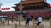 A security person watch over residents passing in front of Tiananmen Gate in Beijing, June 4, 2023.