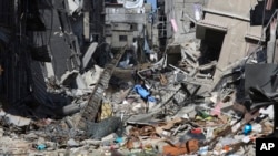 Seorang warga Palestina berjalan melewati bangunan-bangunan yang hancur akibat serangan Israel di Khan Younis, Jalur Gaza, 8 Maret 2024. (Foto: AP)