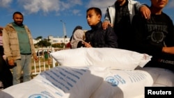 Warga Palestina menerima kantong tepung yang didistribusikan oleh UNRWA di Rafah, selatan Jalur Gaza, pada 21 November 2023. (Foto: Reuters/Ibraheem Abu Mustafa)